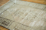 Pale beige distressed Oushak rug revealing muted charcoal geometric field and patterned border.