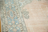 Distressed Oushak carpet: pale blush field, blue and brown fern cartouches.