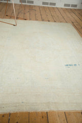 Distressed vintage Oushak rug's fringed edge and worn ivory pile with knot heads.