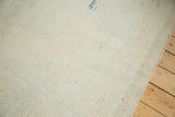Distressed ivory Oushak rug texture showing even wear, pale bronze, and secured side selvage.