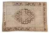 A distressed vintage Turkish Oushak rug with a chocolate brown medallion and worn beige field.