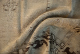 Folded view of a distressed Oushak carpet showing its hand-knotted texture and heavy abrashes.