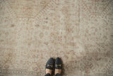 Distressed Oushak rug with low pile, visible foundation, faded beige, ivory motifs; feet.
