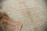 Distressed vintage Oushak carpet featuring soft ivory and beige tones with even wear.