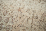 Vintage distressed Oushak carpet pile showing time-softened ivory and pale sand stylized patterns.