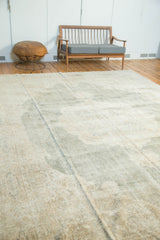 Distressed Oushak carpet showing traditional faded seafoam green and ivory rococo spandrel.