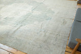 Vintage distressed Oushak carpet displaying rococo corner spandrel, even wear, and pale tones.