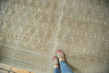 Distressed Kaisary rug's repeating gul motifs in beige and silver, with pale blue arrowed border.