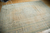 Decorative distressed texture of a vintage Oushak rug with muted apricot and seafoam patterns.