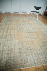 Distressed vintage Oushak carpet with worn texture, pale apricot, and soft green hues.