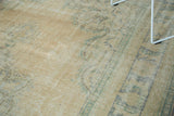 Distressed Oushak carpet pile showing even wear, pale peach, and faded blue motifs.
