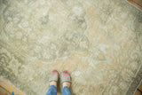 Distressed Oushak rug with muted beige, peach, and sage, highlighting soft texture and curvilinear motifs.