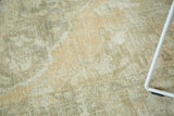Distressed Oushak carpet pile showing faded scrolling elements in beige, silver, and apricot.