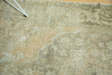 Artfully distressed vintage Oushak rug showcasing faded peach, beige, and silver scrolling designs.