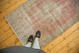 Distressed vintage Oushak rug, with a faded raspberry field, subtle floral patterns, and soft worn texture.