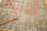 Distressed Oushak rug shows faded raspberry field with potted flowers, green vines, and worn texture.