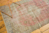 Vintage distressed Oushak rug corner with muted lotus and vine border, faded raspberry field.