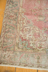 Distressed vintage Oushak rug corner showing time-softened raspberry, blue, and beige lotus border.