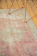 Textured pile of a distressed Oushak rug, with faded raspberry red and pale floral motifs.