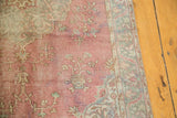 Distressed Oushak rug showing worn raspberry field and pale blue lotus border design.