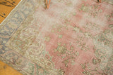 Distressed vintage Oushak rug with faded raspberry, blush, and soft green floral patterns.