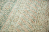 Soft sea foam green, blush, and ivory patterned weave of a distressed Oushak rug.