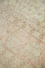 Distressed texture of vintage Oushak carpet, showcasing faded blush pink vinery and ivory.