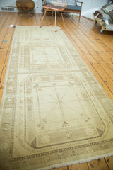 Distressed corner of a vintage Oushak runner, showcasing geometric gul motif and fringe.