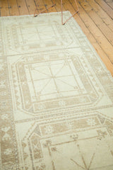 Distressed vintage Oushak rug with a geometric gul motif in antique ivory and sand.