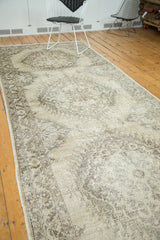 Distressed texture and faded serrated Oushak motif in beige and platinum on a vintage runner.
