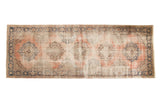 Artfully distressed Oushak runner with dusty rose field, central navy medallions, and geometric border, 4'11