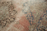 Distressed Oushak rug close-up with worn dusty rose pile, visible foundation, and knot heads.