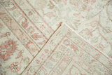 Distressed Oushak rug folded corner, showing ivory, blush pile texture with even wear.