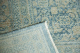 Detail of distressed dark teal pile with dusty gold, revealing hand-knotted foundation and fringe.