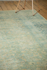 Angled view of distressed pile texture on vintage Meshed carpet with faded blue and beige floral patterns.