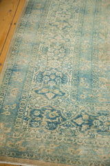 Distressed floral patterns and ornate cartouche border of a vintage Meshed rug.