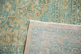 Distressed corner of vintage Persian Meshed rug, muted seafoam and pale gold floral pattern, hand-knotted back.