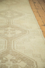 Detailed view of the distressed Oushak runner's short pile and geometric motifs in ivory and beige.