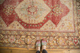 Distressed Oushak carpet, showing worn red field and pale coffee brown floral border.