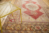 Distressed diamond medallion with pomegranate red, beige, and saffron floral motifs on vintage Oushak.