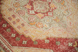 Distressed Oushak pile showing knot heads, light foundation, and blended red-sand tones.