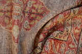 Folded distressed Oushak rug close-up, highlighting worn cherry red pile and visible foundation.