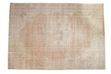 Distressed vintage Oushak rug: pale blush field, ornate ivory medallion, faded pale blue details.