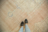 Vintage distressed Oushak carpet displaying faded blush and ivory with blue motifs and even wear.