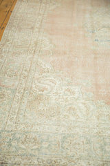 Pale blush and ivory distressed Oushak rug pile with faded curvilinear patterns.