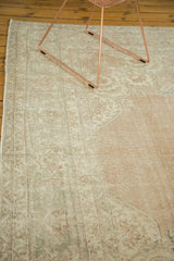 Distressed ivory and pale blush floral motifs on a vintage Oushak rug section.