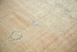 Distressed vintage Oushak carpet's worn pale blush and ivory pile with faint blue motifs.