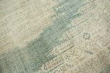 Distressed Oushak carpet texture revealing faded green and beige geometric floral motifs.