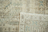 Distressed vintage Oushak rug showing hand-knotted backing, fringe, and geometric design.