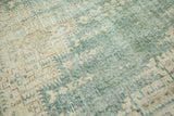 Distressed Oushak rug texture with visible knot heads and muted dark green and sand hues.